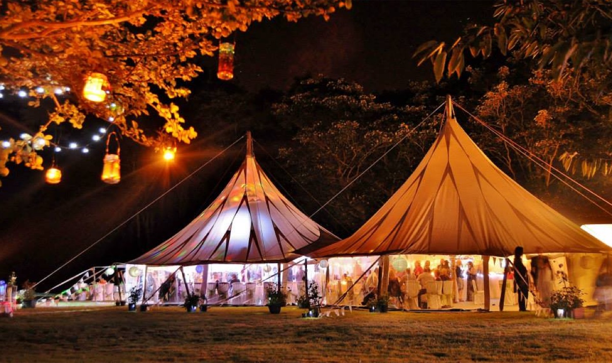 Two Big Event Tent canvas marquees lit up at night with hanging lanterns at a wedding reception