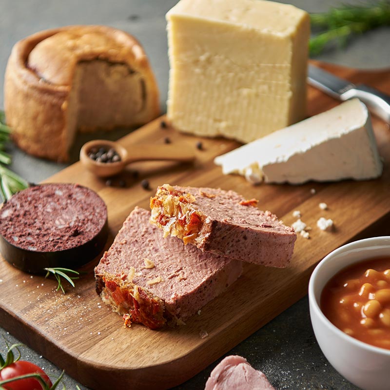 Charcuterie and cheese board featuring a pork pie, aged cheese, brie, pâté slices and black pudding — representative of Sessions of Worcestershire's catering butchery products